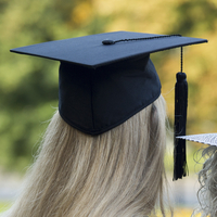 A graduate in gown and caps and his mother celebrate their graduation.